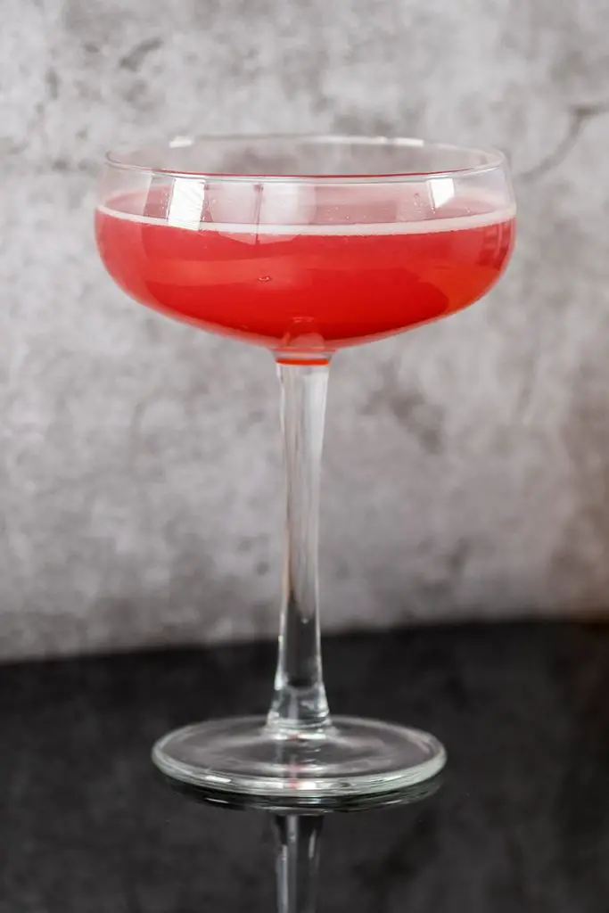 Davis Cocktail in a coupe cocktail glass on a black reflecting table and marble background