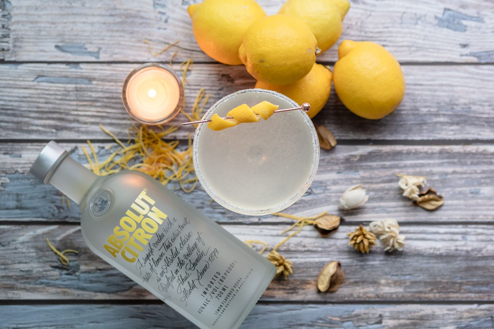 lemon drop with absolut citron on a wooden table with lemons, candle and dried flowers