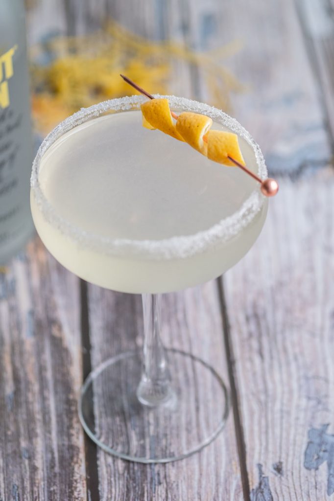lemon drop garnished with a twist of lemon on a wooden table