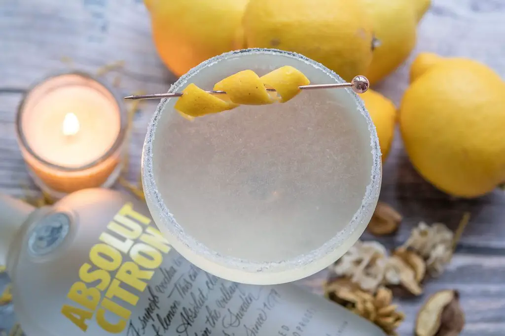 lemon drop with absolut citron on a wooden table with lemons, candle and dried flowers
