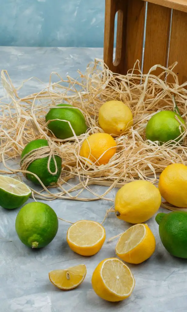 Lemons and limes with wooden crate on grey and blue marble background to use for homemade cocktail ingredients