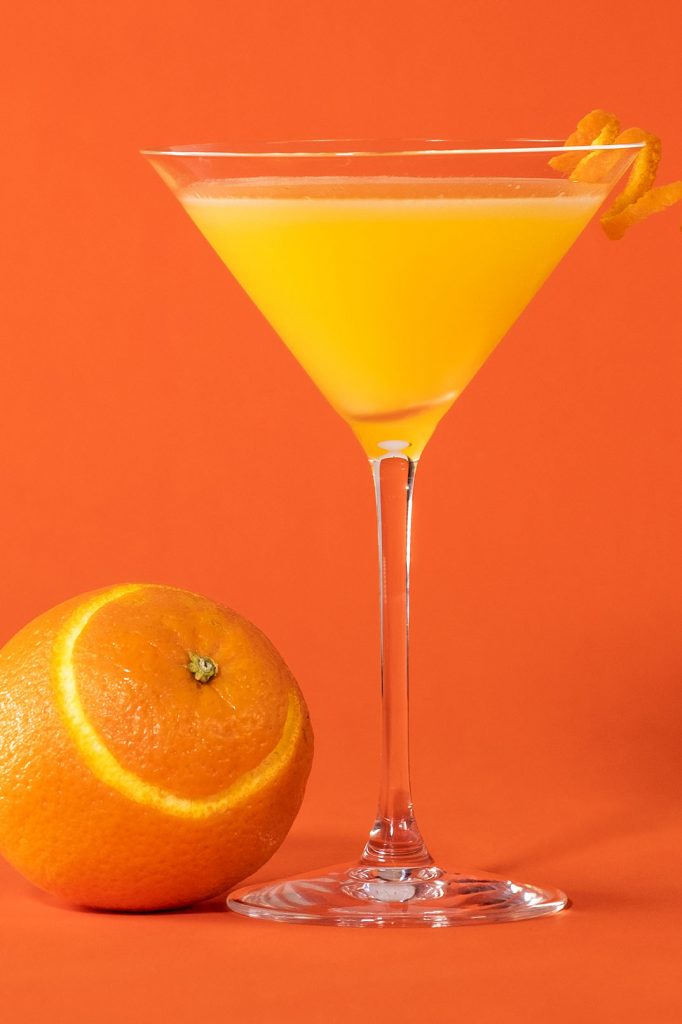 Orange martini with a partially peeled orange
