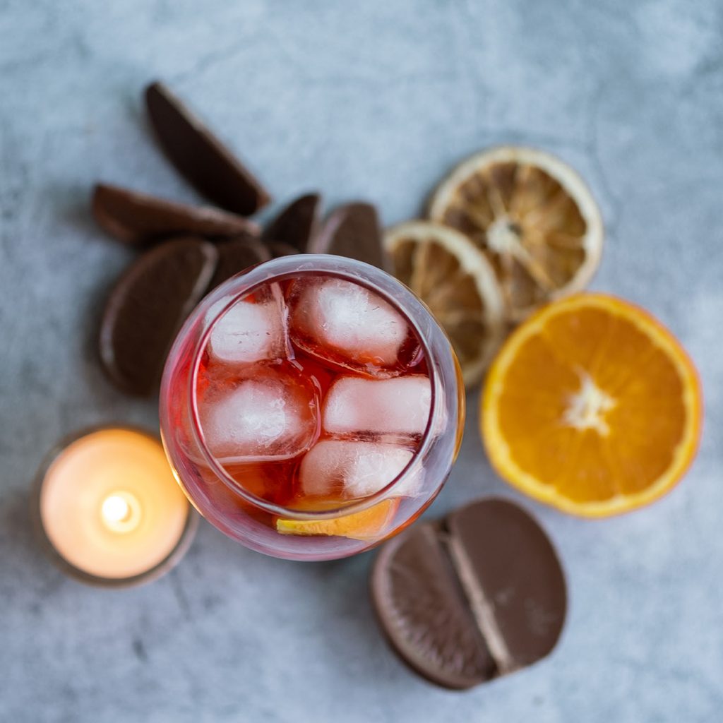 Tabletop view of a glass of Negroni cocktail.