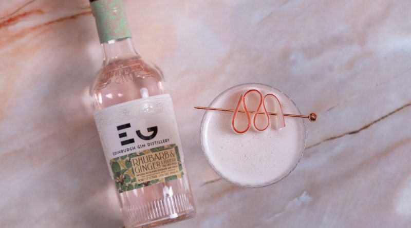 Top view of a rhubarb ginger gin cocktail with a bottle of edinburgh gin distillery's rhubarb ginger gin.
